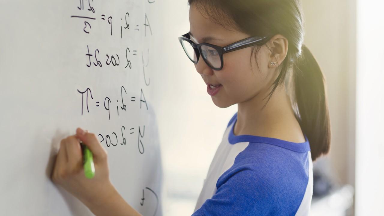 Mädchen schreibt mathematische Formeln an die Tafel