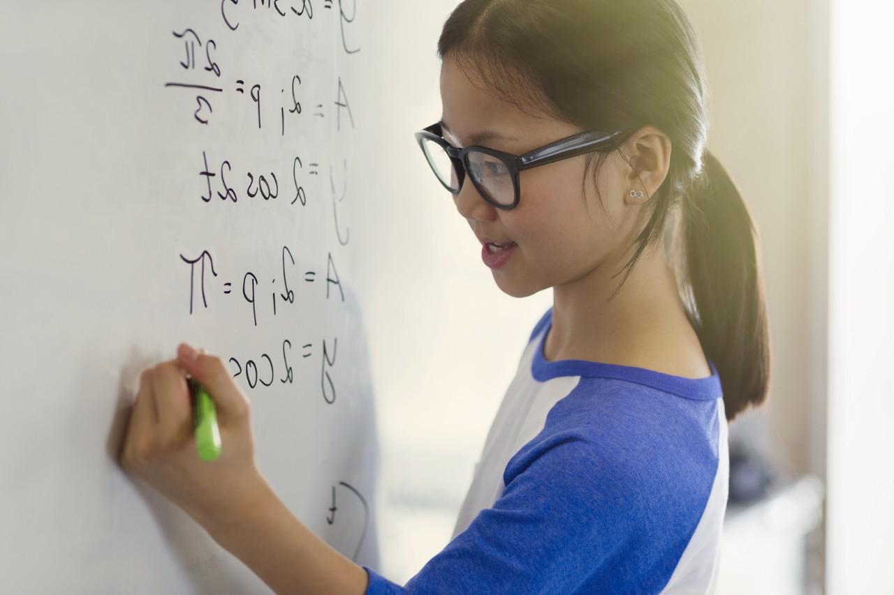 Ein junges Mädchen rechnet an einem Whiteboard