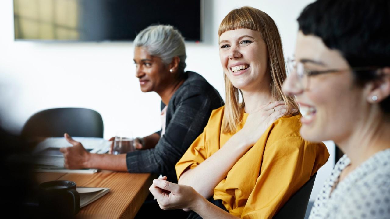 Smiling entrepreneur with female coworker looking away in meeting at workplace
