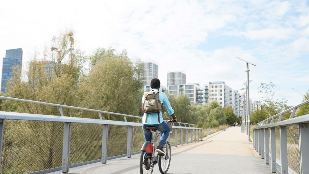 一个女孩骑着自行车过桥去了一个城市.