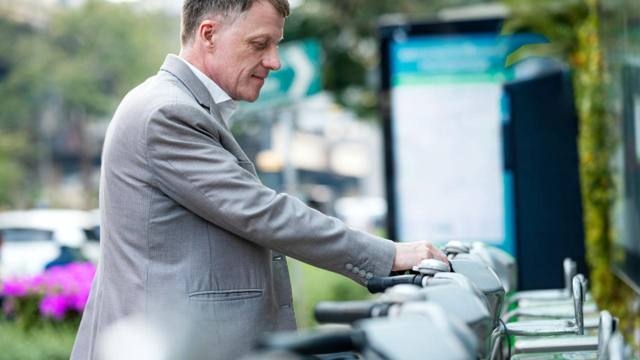 一位商人在公共自行车服务区挑选自行车. 共享单车系统概念.