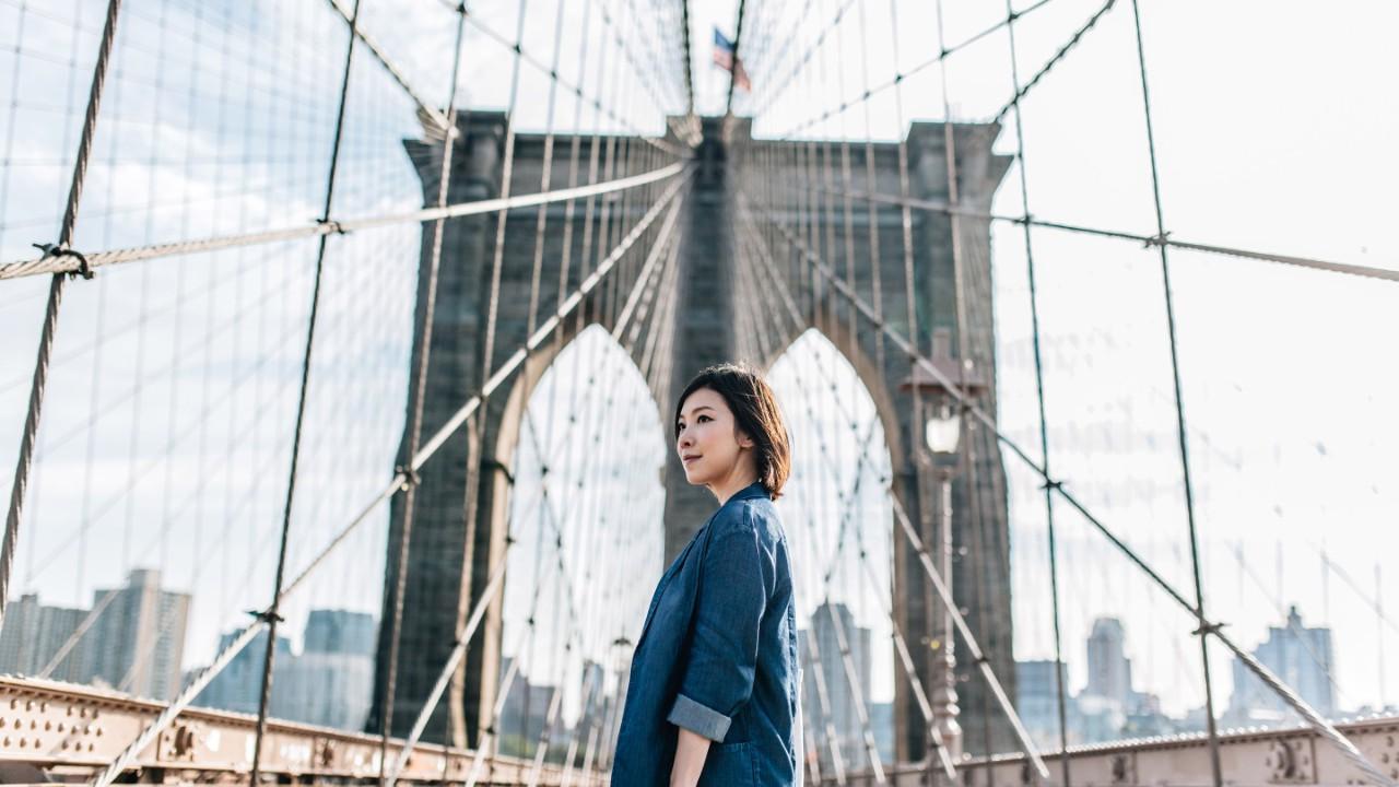 布鲁克林大桥上的年轻女商人反对纽约城市景观