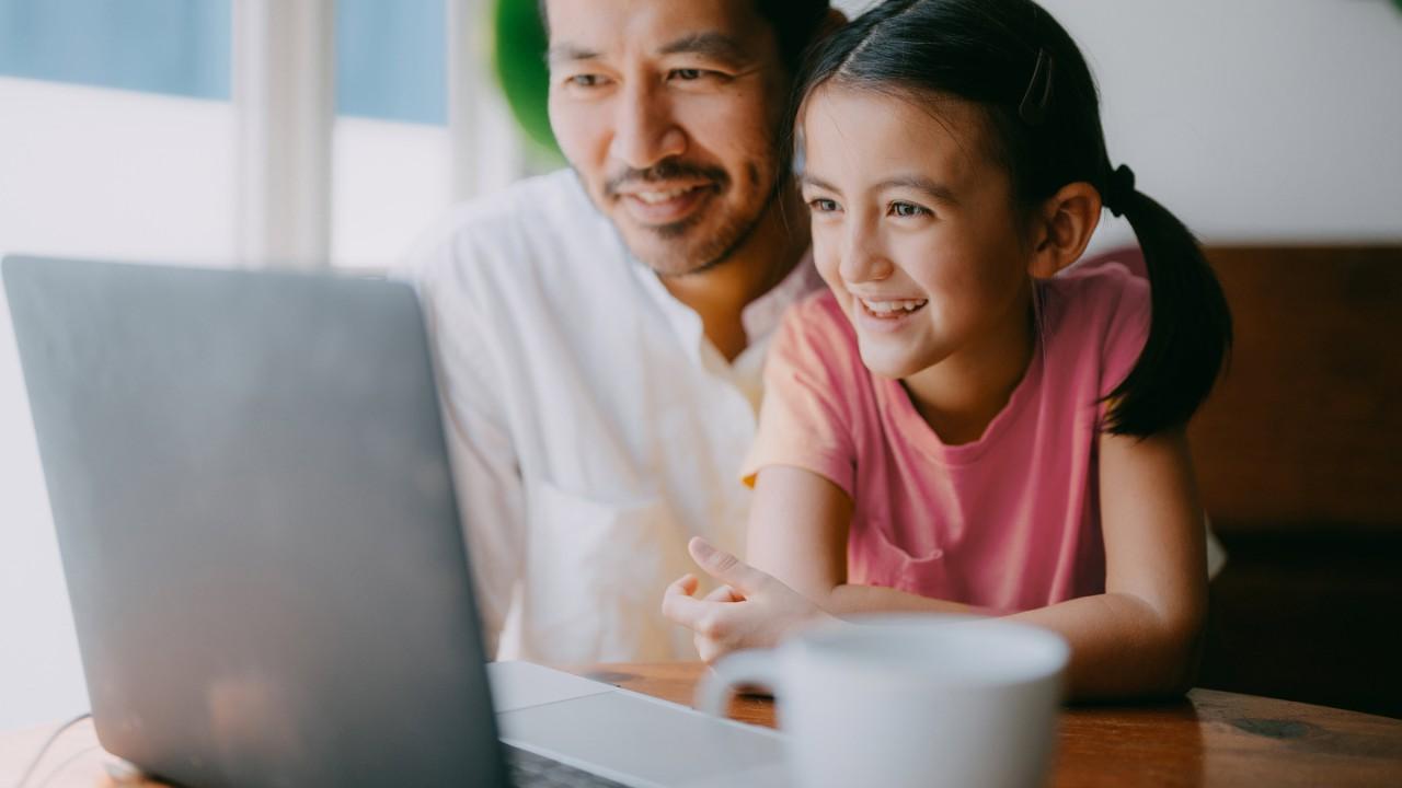 父亲和女儿在video上，在laptop家庭。